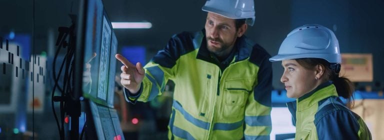To fabrikkarbeidere planlegger smart industri sikkerhet på en dataskjerm.